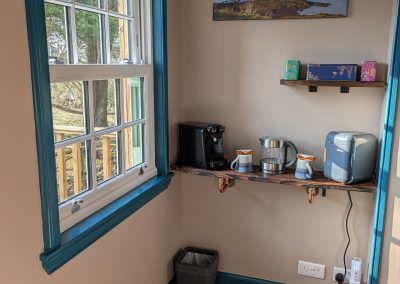 Room entrance with front window showing tea and coffee, mini fridge, kettle and coffee machine